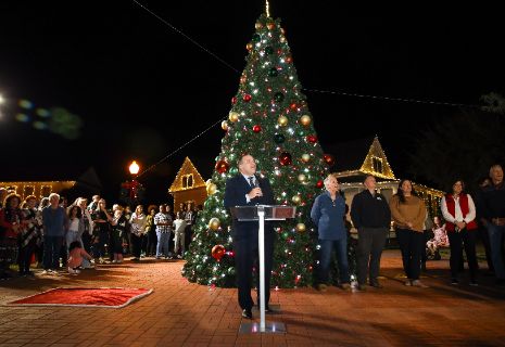 A person standing at a podium with a crowd of people around himDescription automatically generated